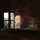 A lit up phonebox in dark surroundings