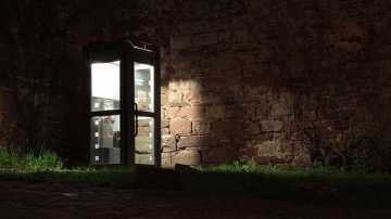 A lit up phonebox in dark surroundings