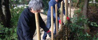 Volunteers construct a fence with natural materials