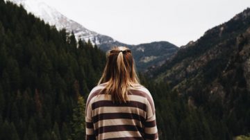 lady stood in front of mountains as if looking towards a journey