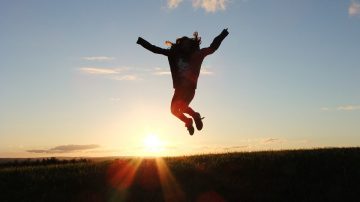 Person jumping in the air in front of sunrise