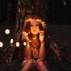 These well worn toys: girl sitting with a crown of fairy lights