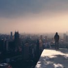 hooded person alone looking over a city