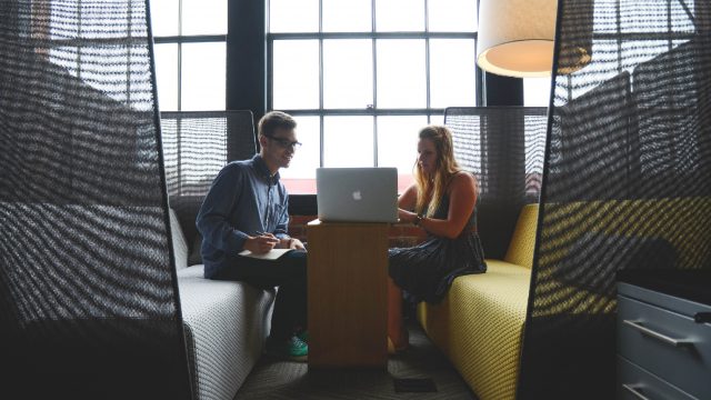 2 people sitting opposite each other on a computer